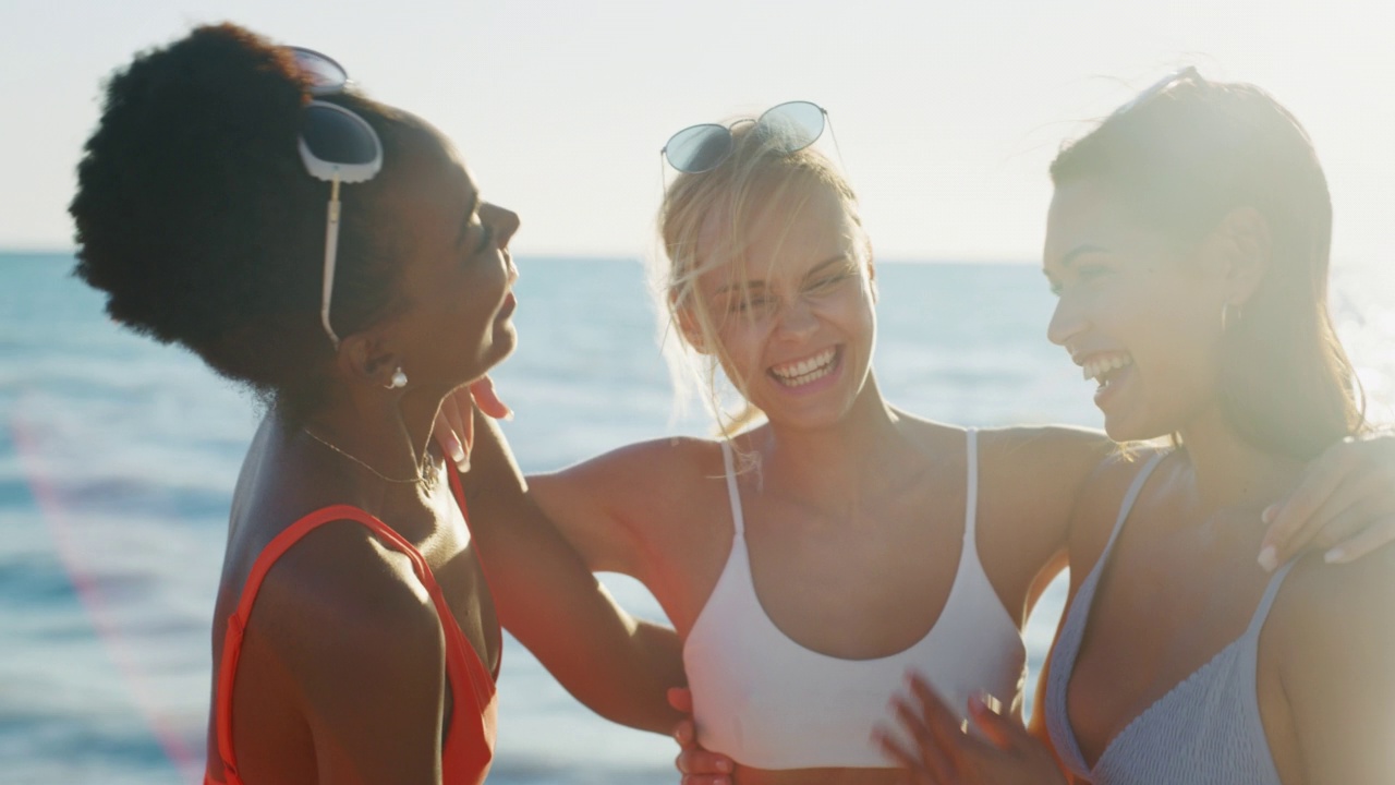 身穿比基尼的多民族少女们在夕阳下的海边一起享受暑假。视频下载