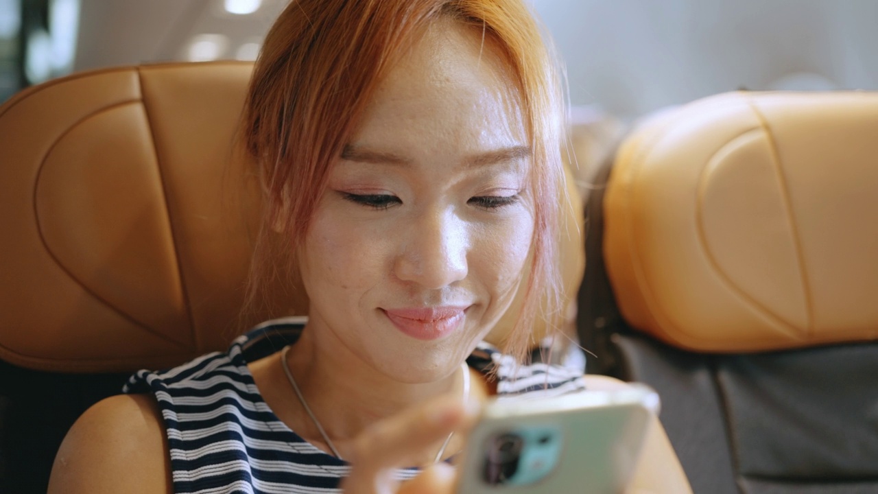 年轻女子在飞行中使用智能手机时很开心。视频素材