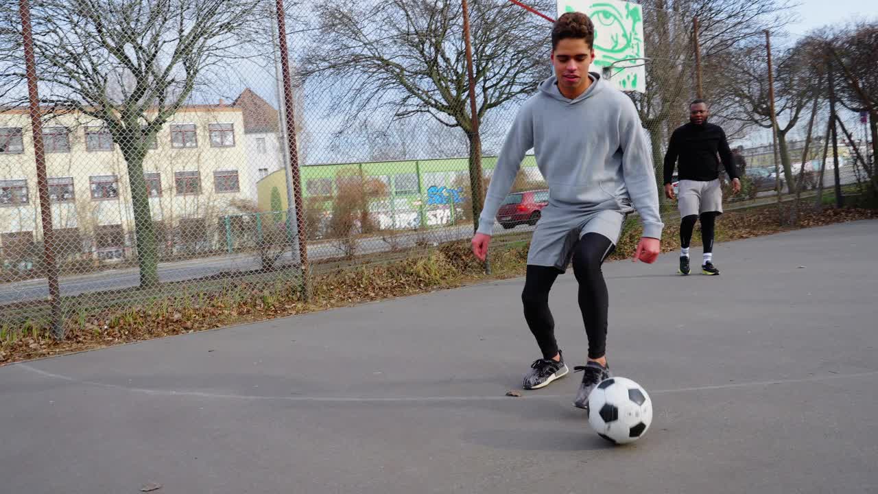 年轻人在城市运动场上踢足球。视频素材