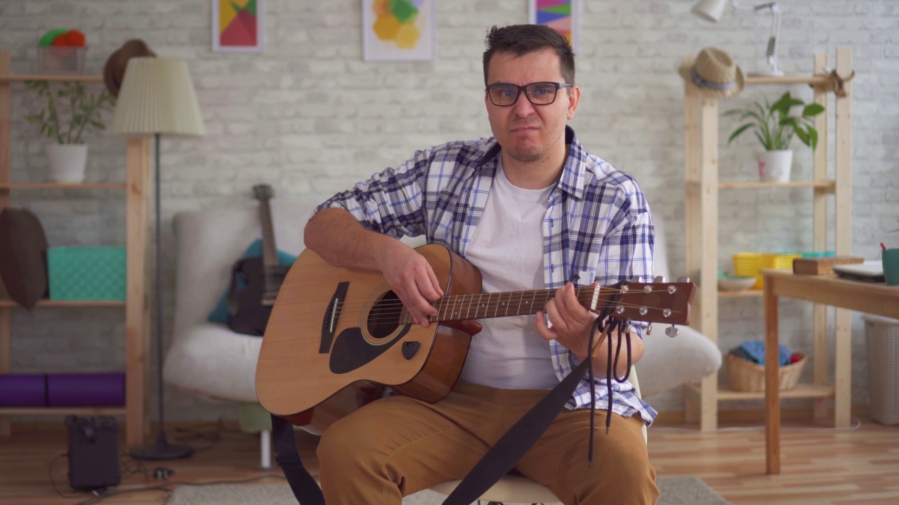 戴眼镜的年轻音乐家不会弹吉他视频素材