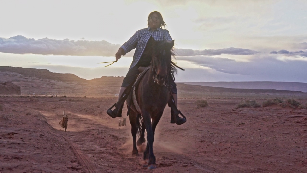 一个年轻的纳瓦霍妇女骑着马飞奔过纪念碑谷附近的沙漠视频下载