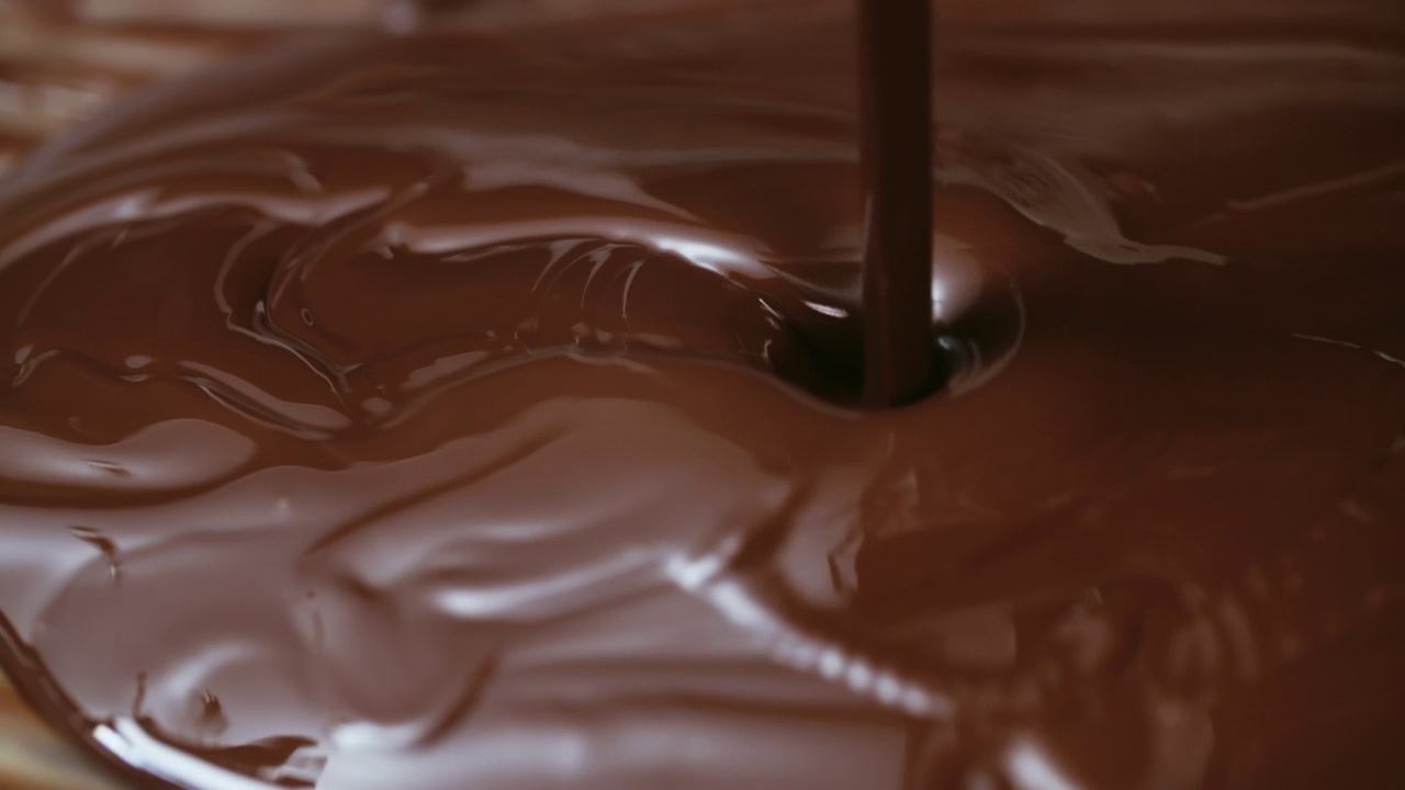 近距离的热巧克力液体流动，熔融牛奶巧克力或棕色焦糖酱。烹饪手工巧克力甜点和糖果。糖果视频素材
