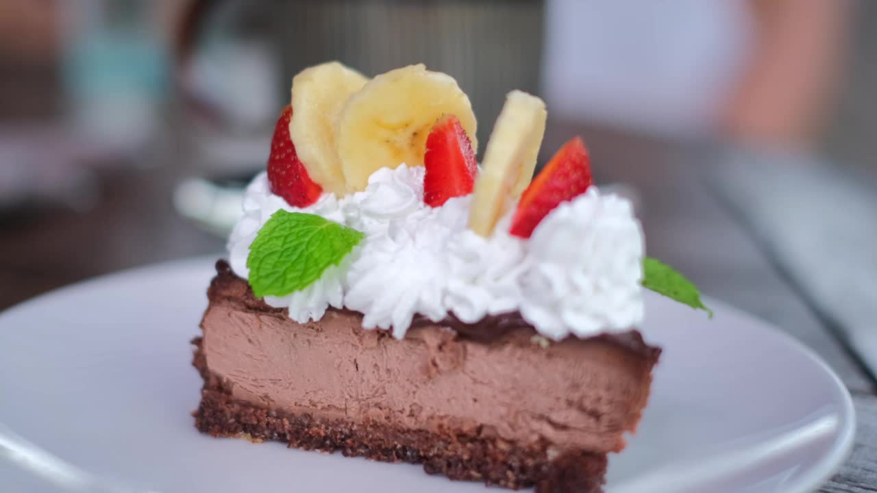 诱人的巧克力蛋糕，点缀着奶油、草莓和香蕉，是咖啡馆里的甜点。一个诱人的甜点不会让你无动于衷，直到你尝试它视频下载