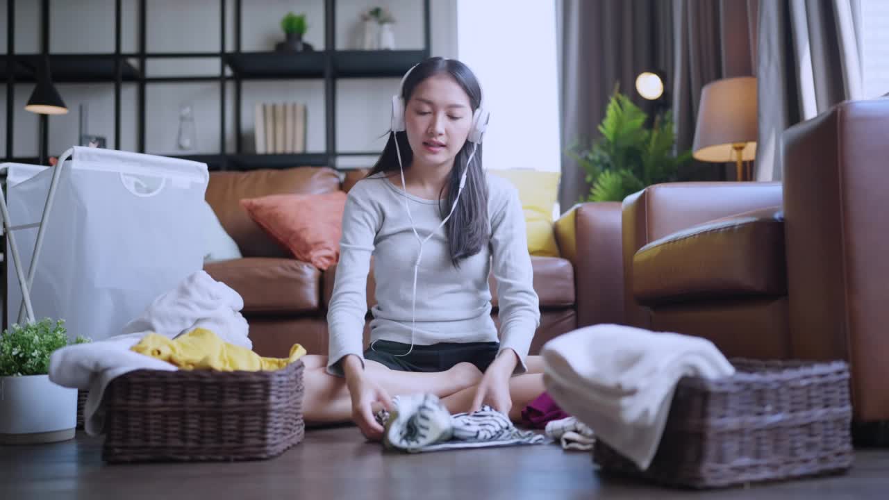 一位年轻的家庭主妇在家里的客厅里用手触摸一叠刚洗过的干净亚麻布视频素材