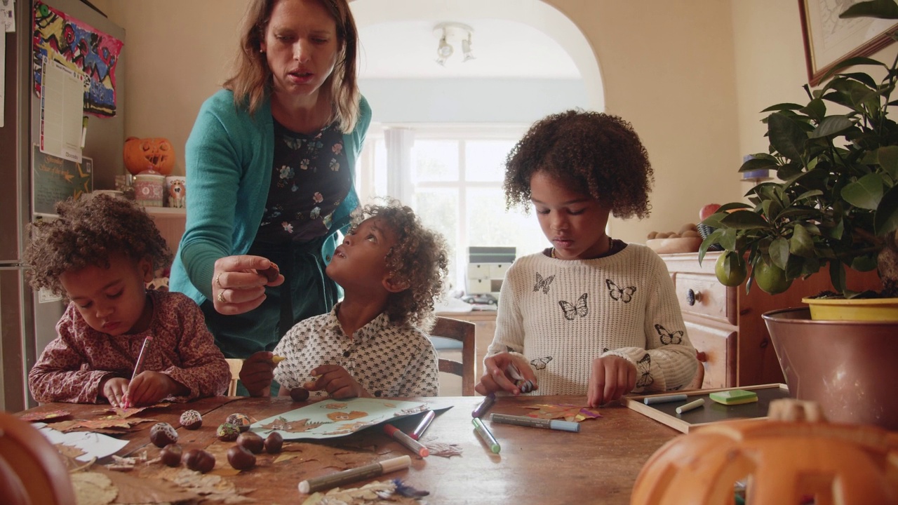 母亲在餐桌上看着孩子们做秋天的手工项目视频素材