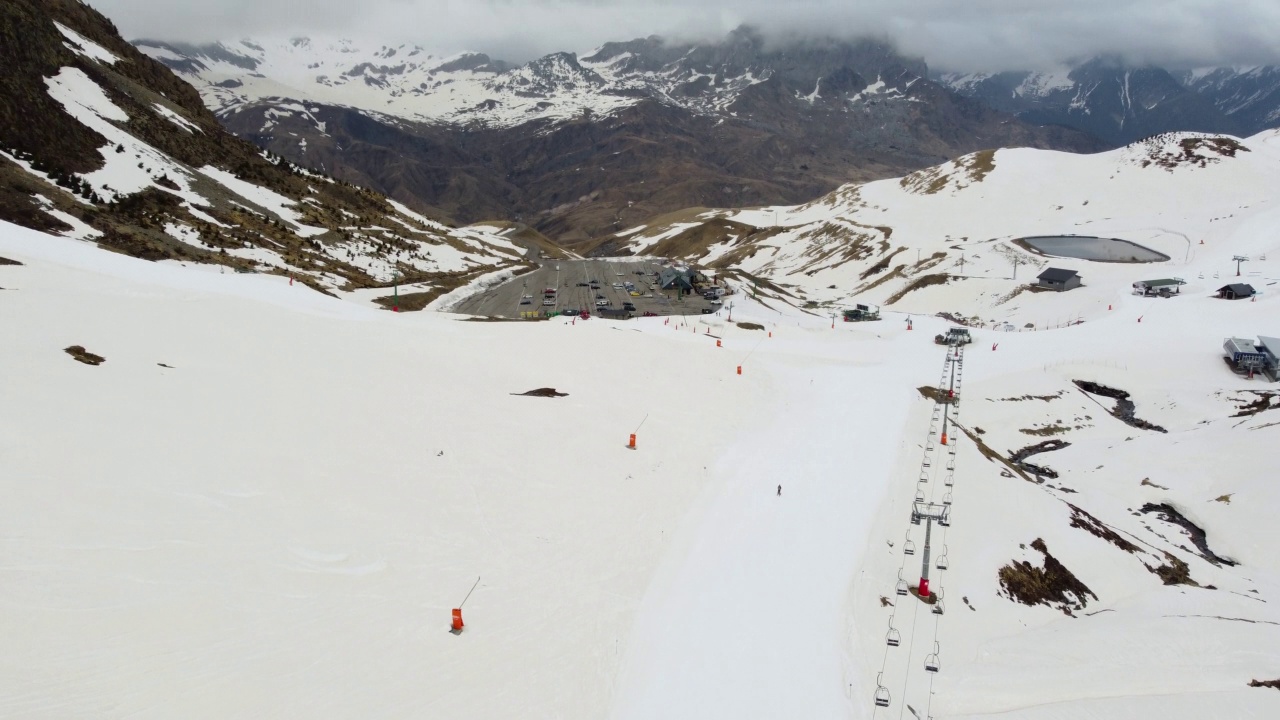 孤独的滑雪者结束了一天的滑雪，沿着滑雪斜坡走向西班牙的Formigal的停车场视频下载