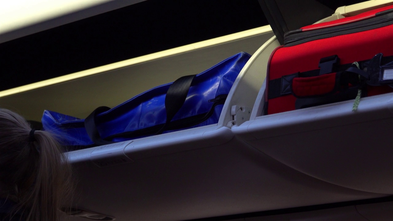 一位空乘人员在整理头顶上的行李柜视频下载
