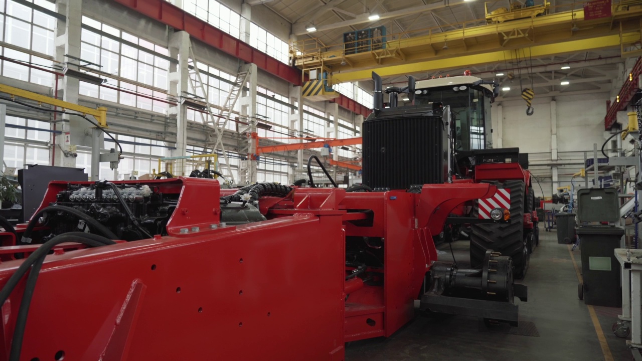 大型红色收割机或拖拉机在工厂生产线上装配，用于农业机械的生产制造视频素材