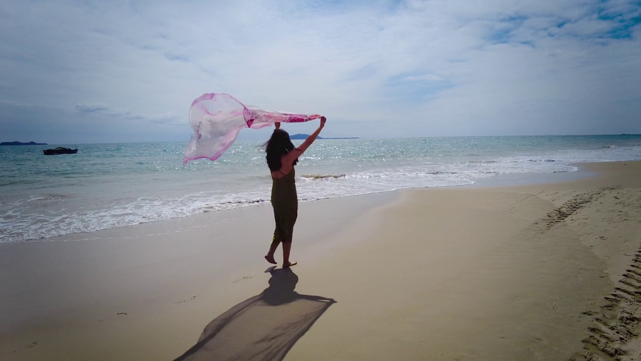 女人挥舞着围巾走在沙滩上视频素材