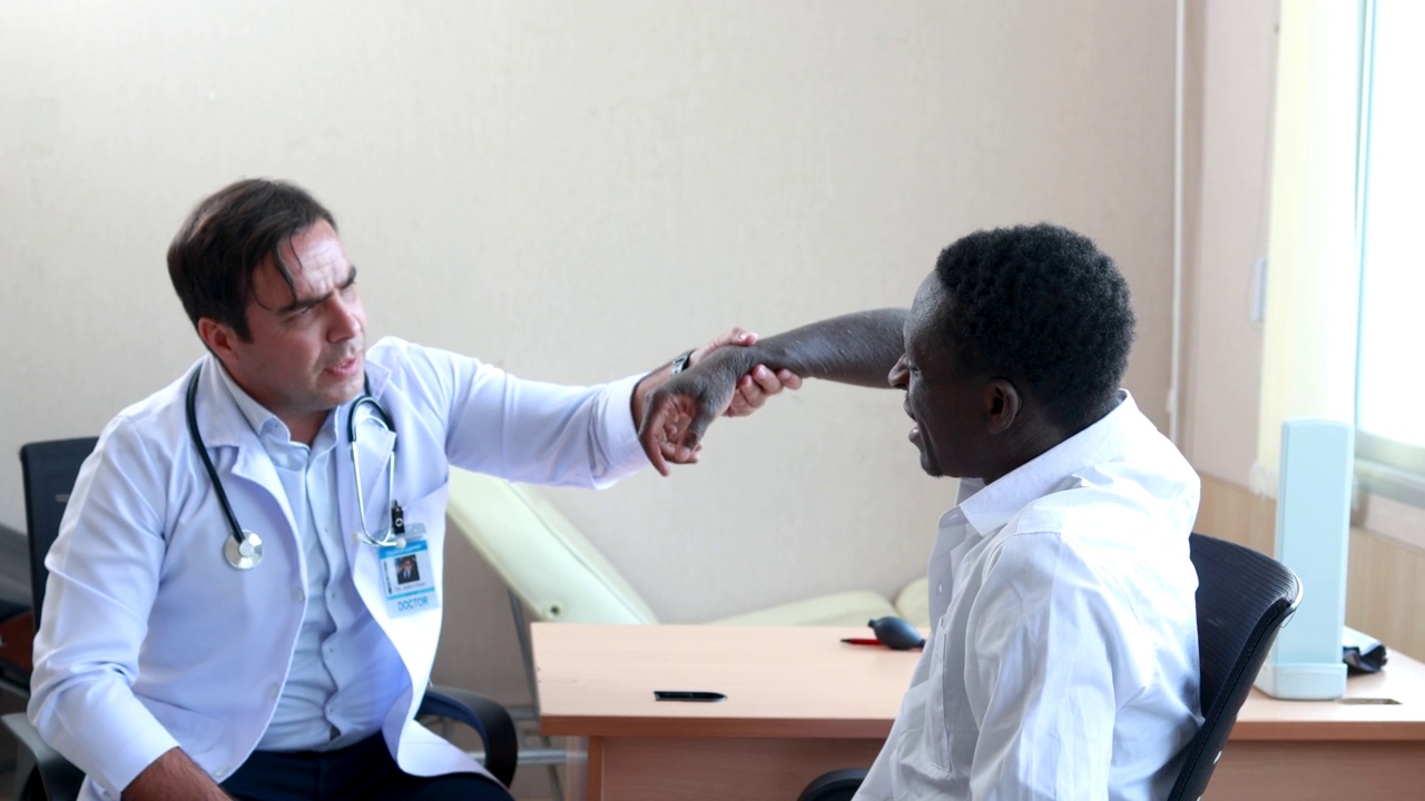 男性骨科医生在诊所检查非洲男性病人的肩膀和手臂视频素材