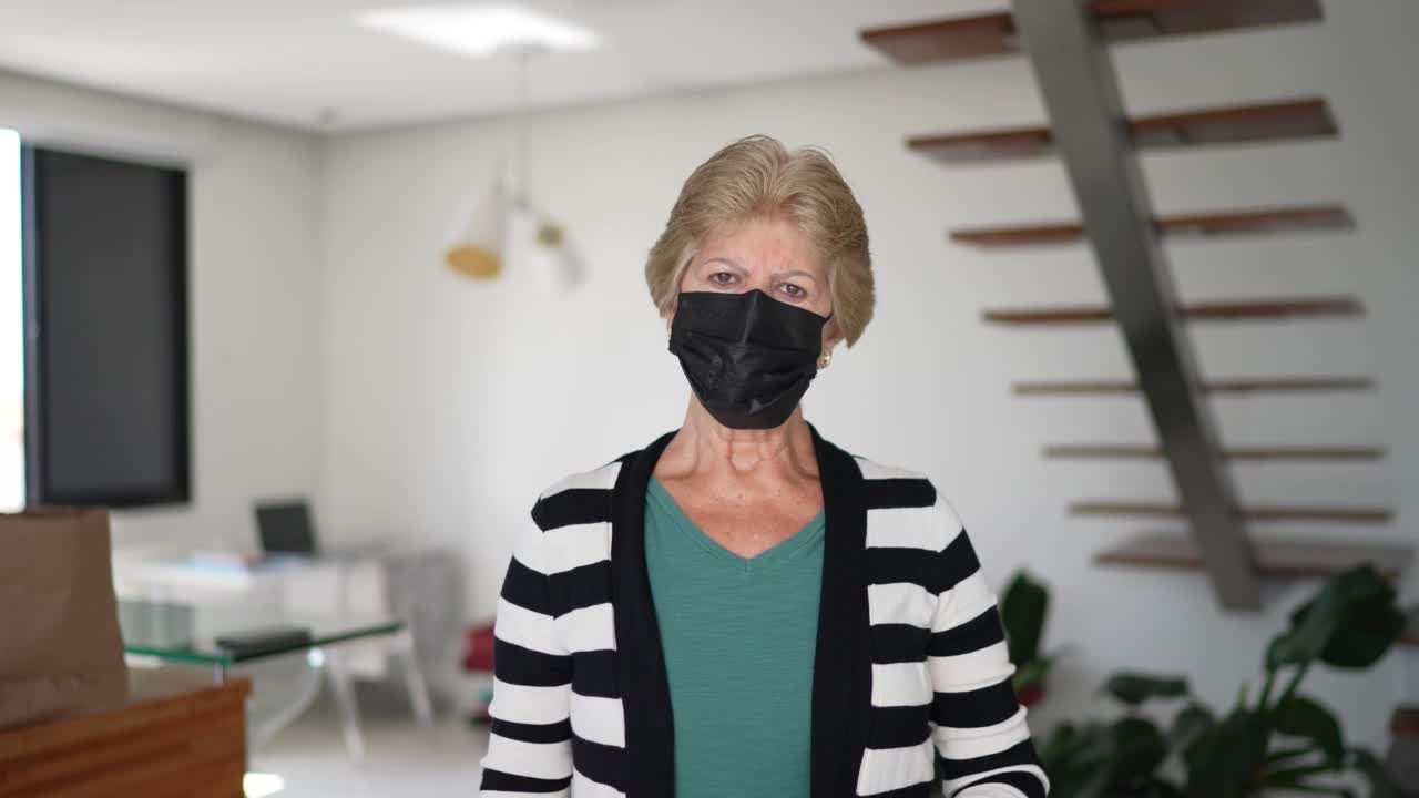 一名老年妇女在家中摘掉口罩的肖像视频素材