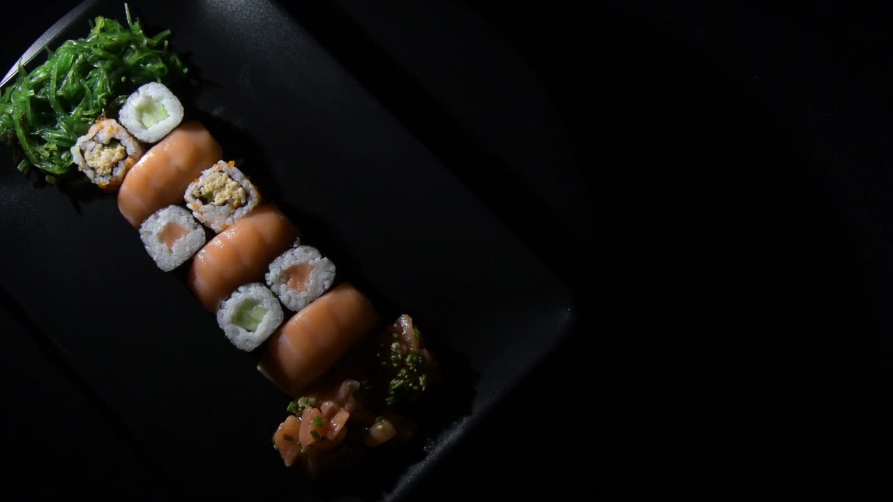 寿司卷集鲑鱼和wakami在黑色的托盘视频下载