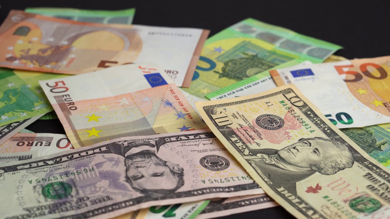钱落在桌子上。大量的欧元和美元纸币投在黑色的背景上视频下载