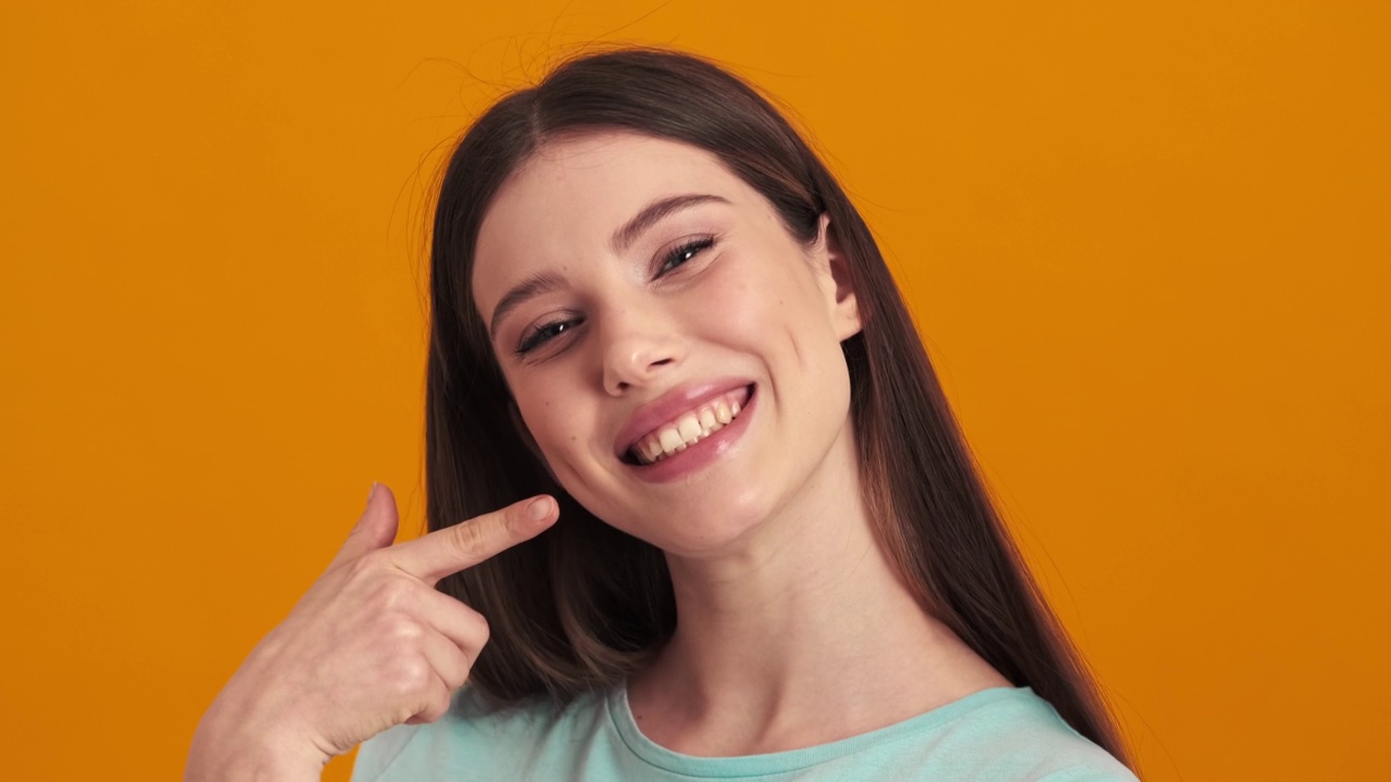 一个快乐的年轻女子正用手指着她站着的完美笑容视频下载