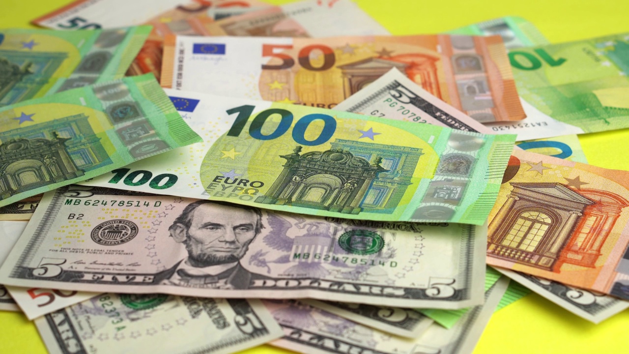 钱落在桌子上。将大量欧元和美元纸币投在黄色的背景上视频下载