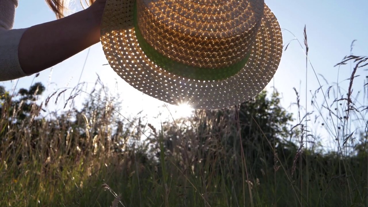夏日的阳光下，一名女子拿着草帽视频下载