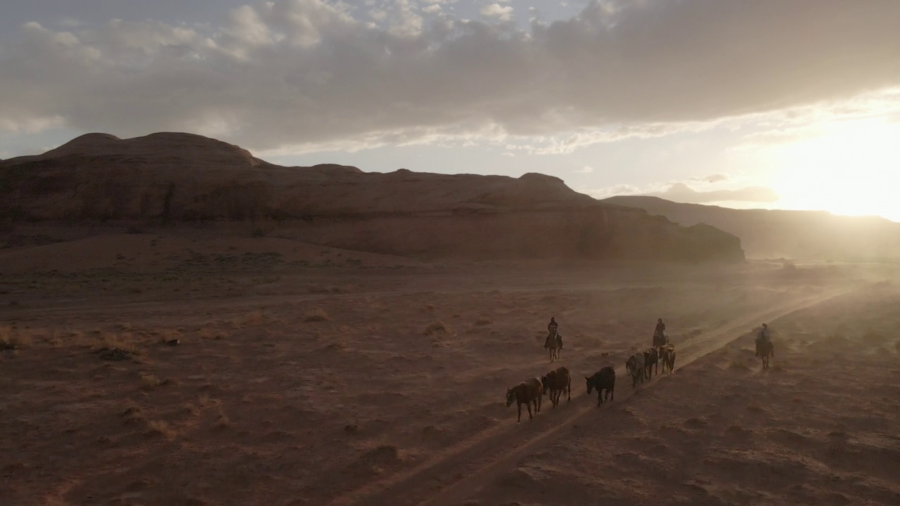 无人机纳瓦霍青少年在亚利桑那州的纪念碑谷部落公园骑马，黄昏时分，在戏剧性的云景下视频下载