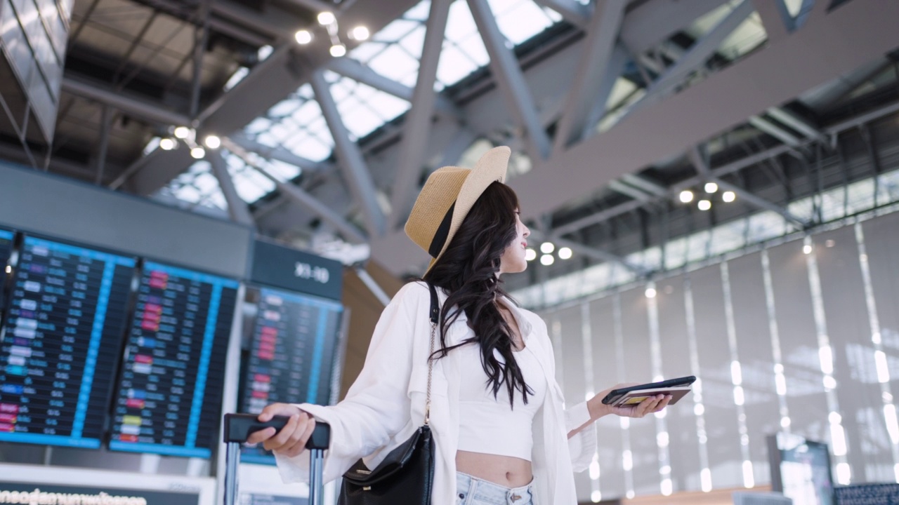 兴高采烈的亚洲年轻女子拿着护照和行李站在机场视频购买