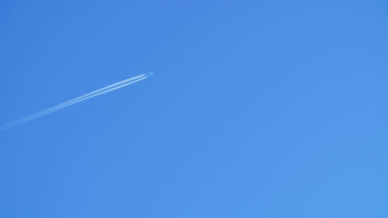 喷气式客机在高空飞行时，在清澈的蓝天上留下了尾迹。视频素材