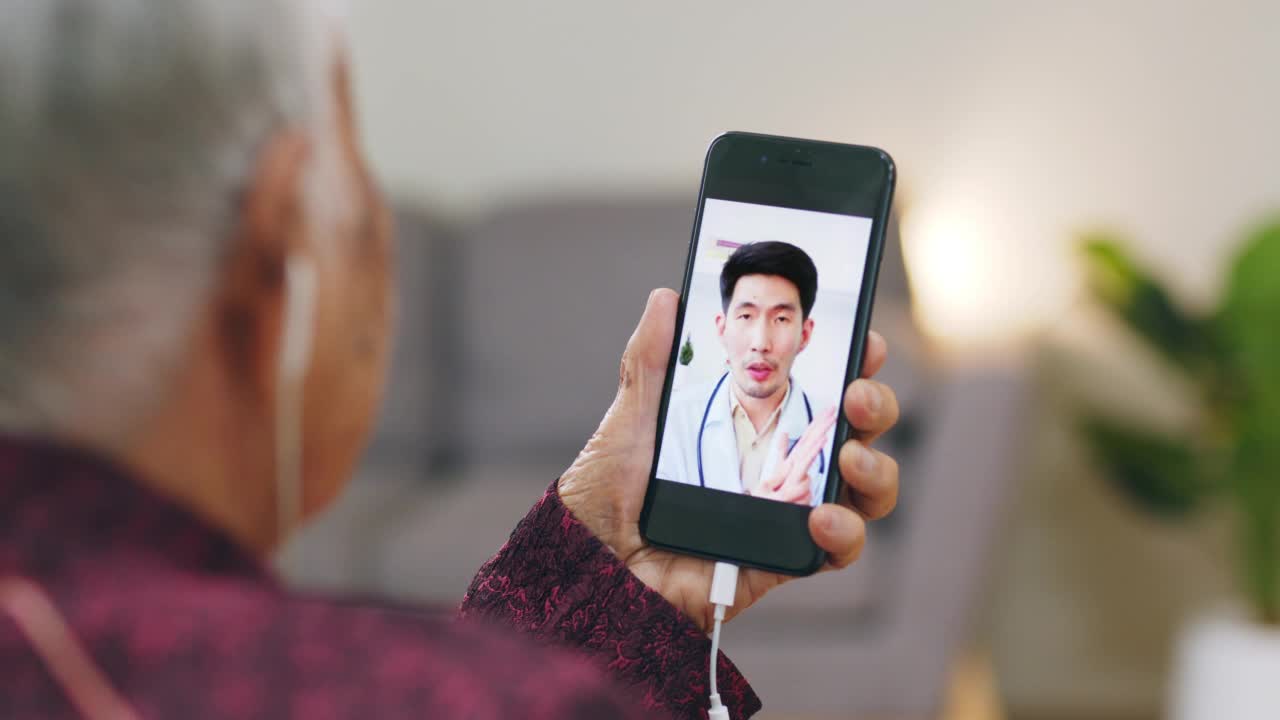 亚洲老年妇女90年代视频通话与医生远程医疗远程保健概念视频素材