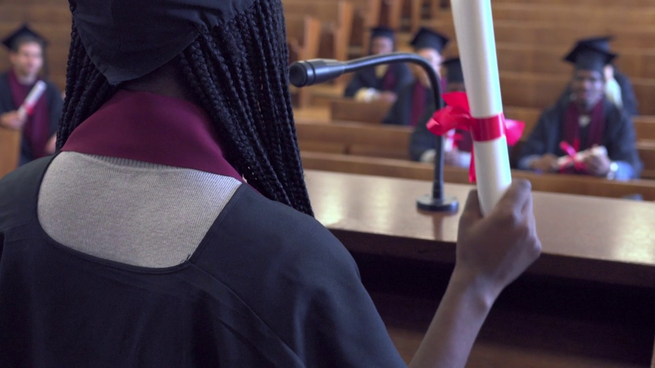一名学生站在舞台上，用麦克风接受毕业证书视频素材