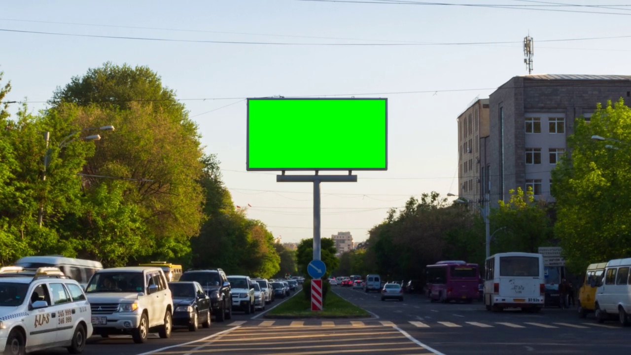 一个以城市交通为背景的绿色广告牌，有汽车、行人、树木、蓝天和建筑。在亚美尼亚，埃里温市。视频下载