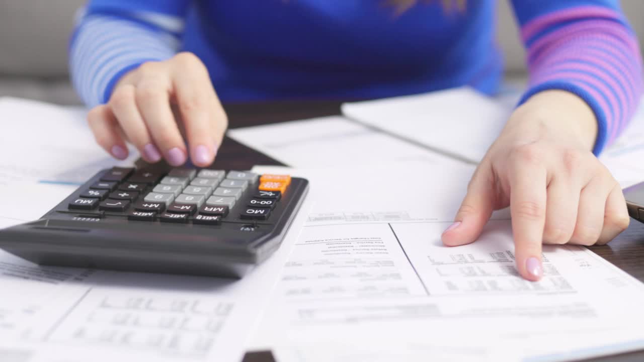妇女在家里用计算器计算家庭账单，做纳税文书工作视频素材