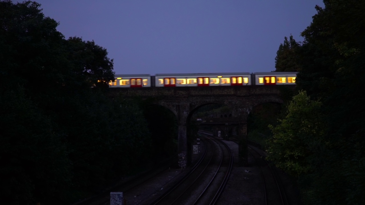 一列灯火通明的火车经过混凝土桥视频下载