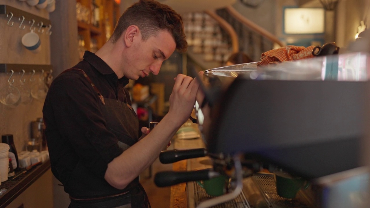 咖啡店里，男咖啡师一边用浓缩咖啡机煮咖啡视频下载