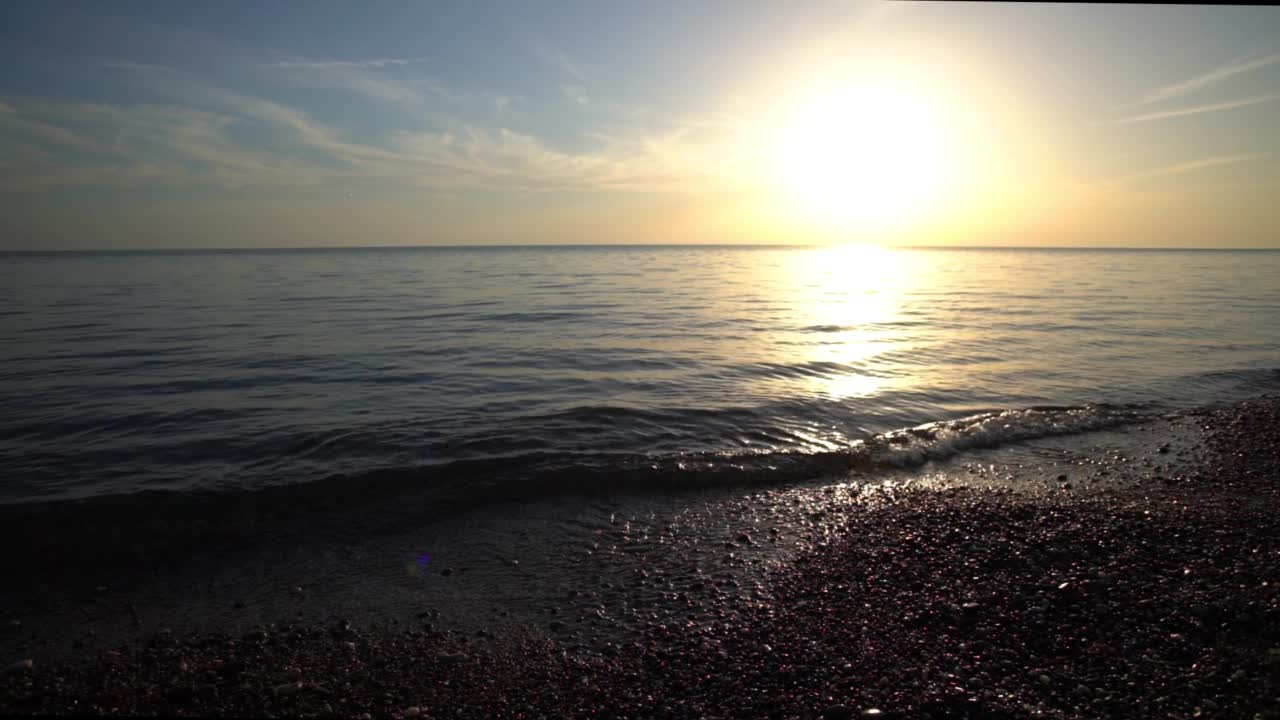 在平静的海面上，明亮的太阳从地平线上落下视频素材