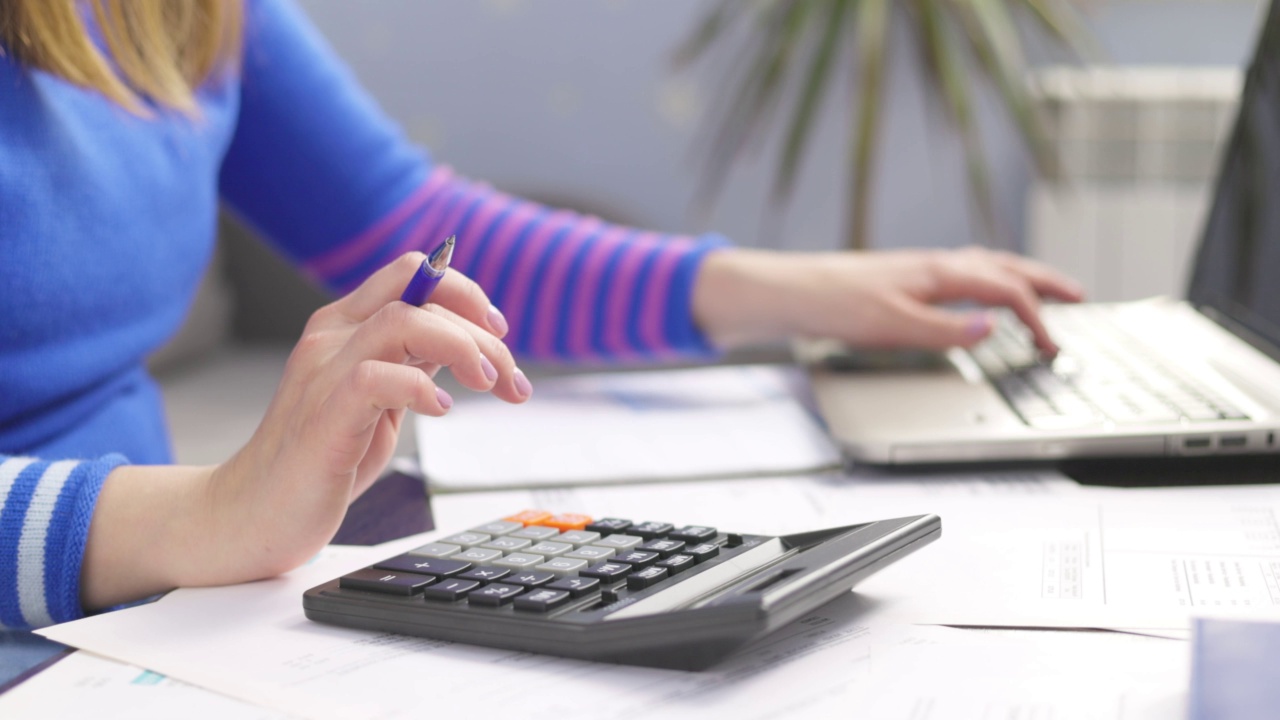 妇女在家里用计算器计算家庭账单，做纳税文书工作视频素材