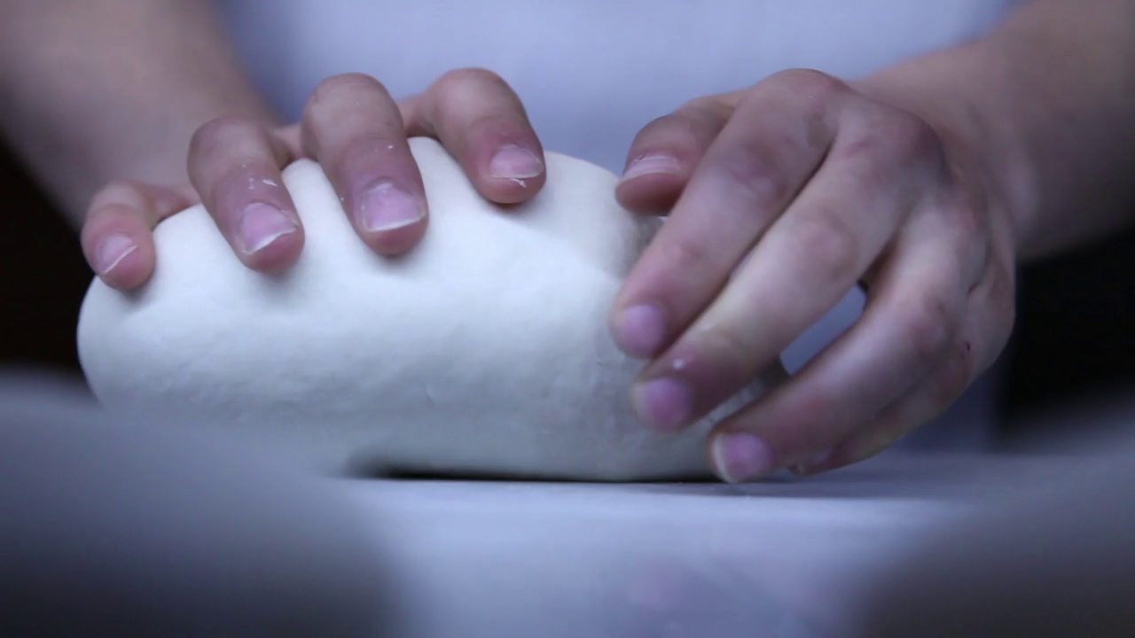 在专业的厨房里，经验丰富的面包师用面粉准备生面团来制作酸面包。视频下载