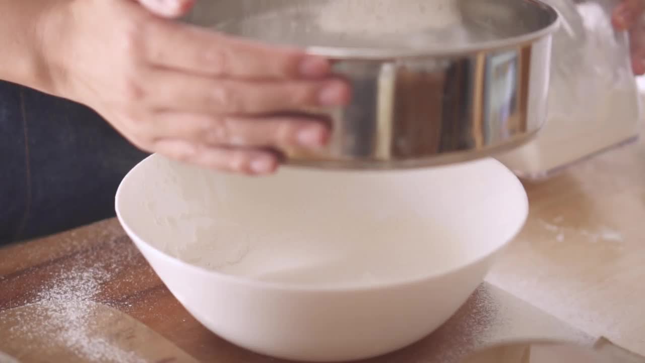 特写手女人筛面粉在厨房慢动作视频素材