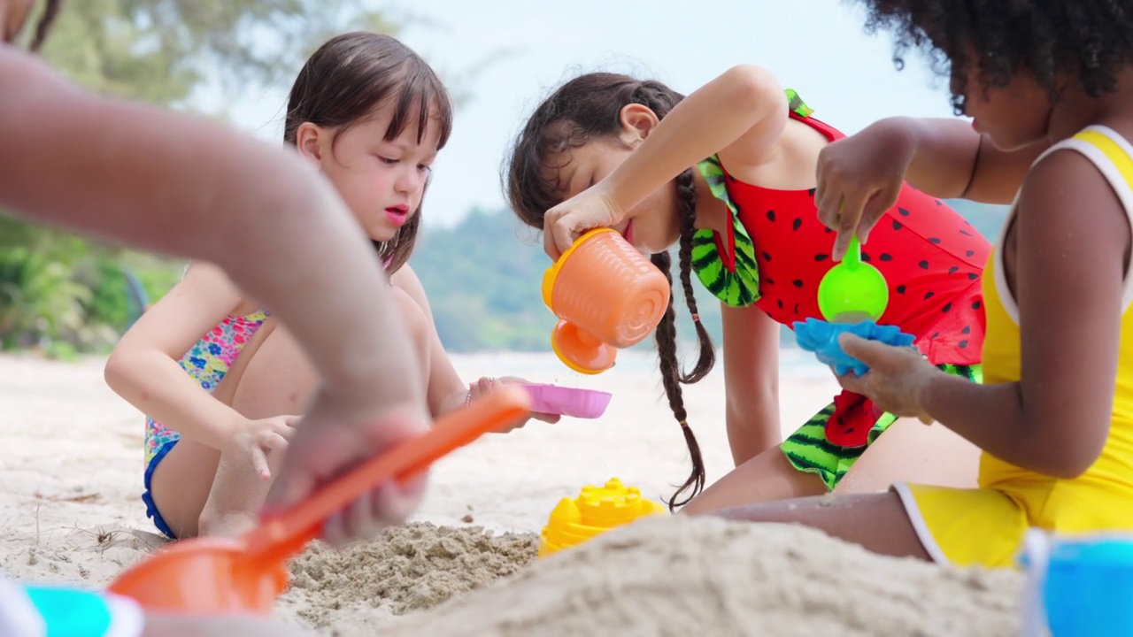 4K一群多样性的孩子在暑假的海滩上一起玩沙滩玩具。视频下载