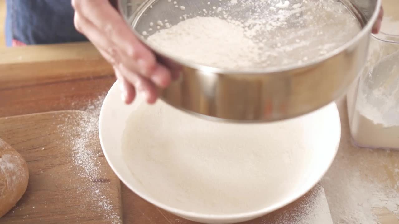 特写手女人筛面粉在厨房慢动作视频素材
