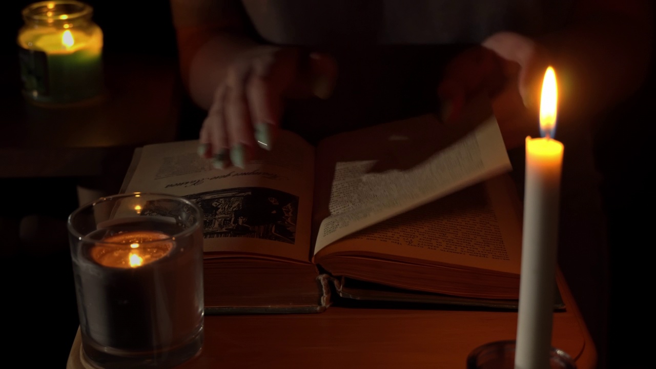 女孩晚上在烛光下读一本旧书视频素材