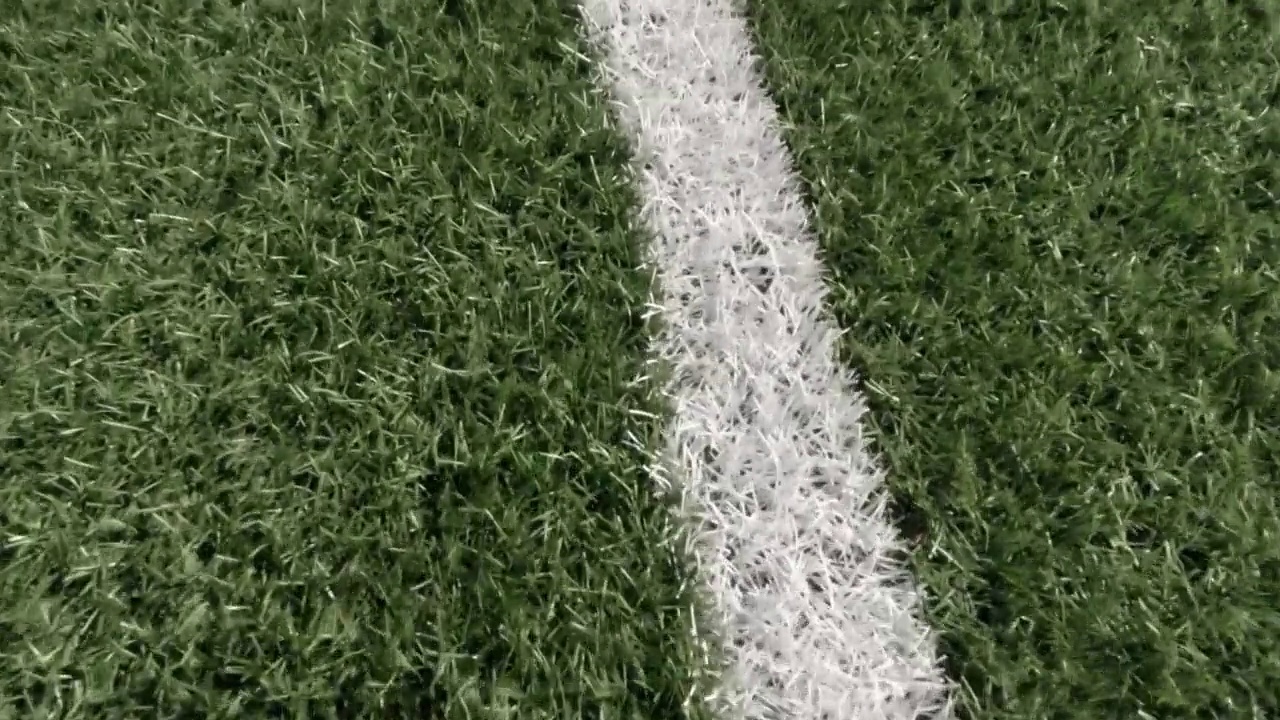 白色条纹线在人工绿色足球场的背景从上面。近距离视频素材