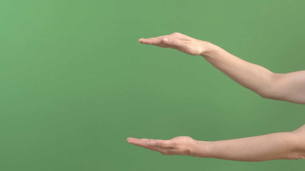女人手牵着手，仿佛在手掌之间展示某种虚拟的、看不见的东西。女性手在绿屏彩色键背景上延伸广告版面视频素材