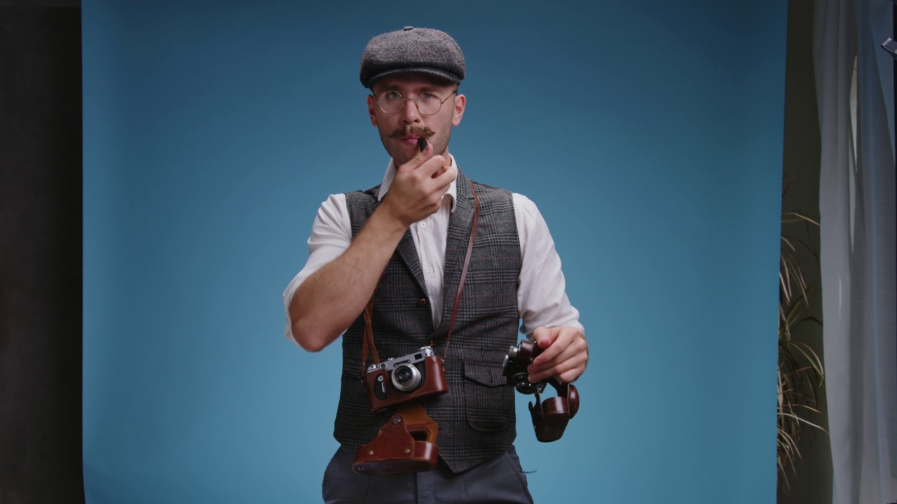 近距离的老式摄影师戴着眼镜和复古西装与老式机械胶片相机的快门手势与他的手和排队的人在工作室的合影视频下载