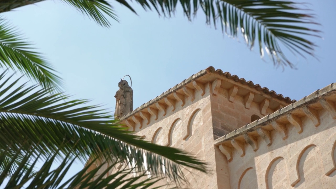 在基督城波尔图的罗马天主教堂的顶部，仰望卡梅尔山圣母的小雕像，前景中棕榈树的叶子在缓慢的风中移动视频下载
