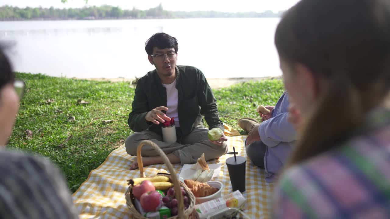 一个年轻人正和朋友们在湖边野餐。视频素材