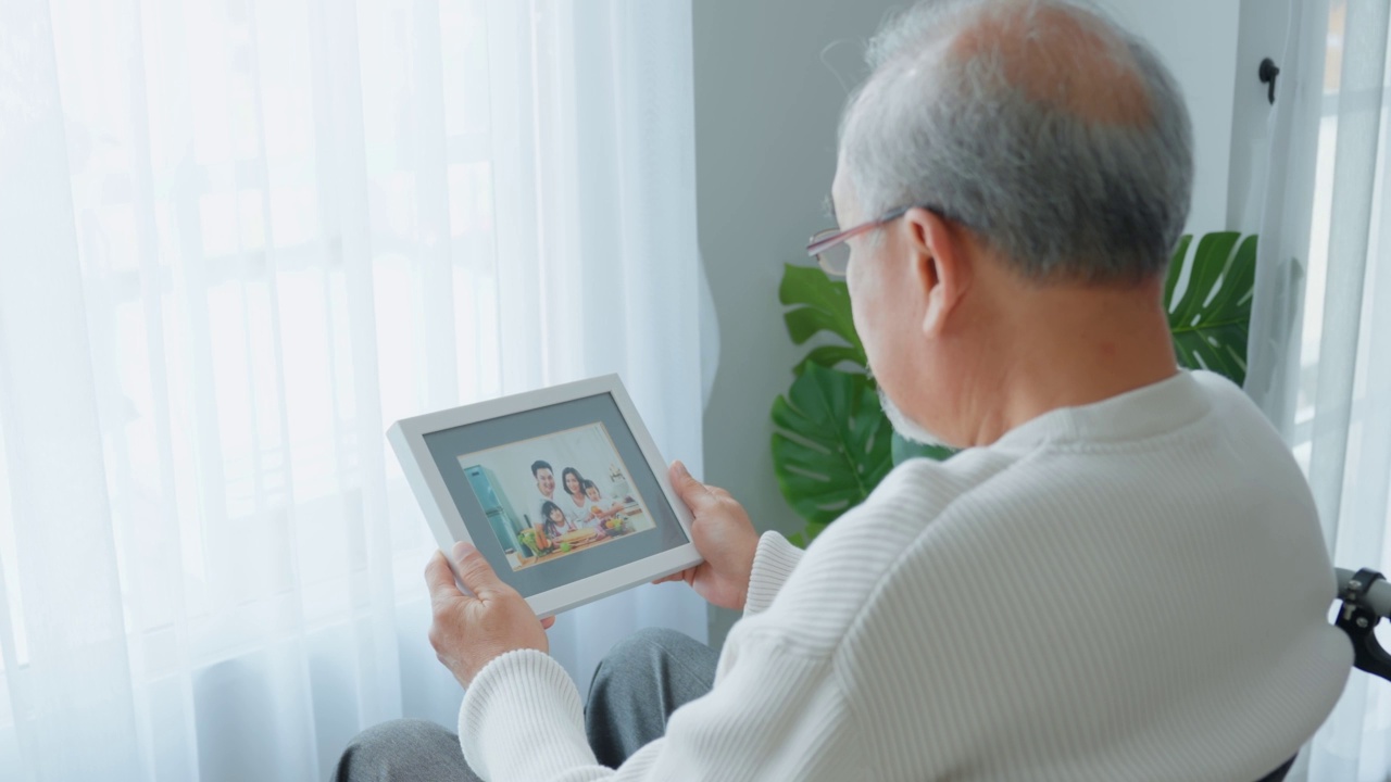 亚洲老年男性退休后独自坐在轮椅上，呆在家里。不快乐的老年残疾人感到孤独和担心卫生保健问题。医院保健和医疗理念视频素材