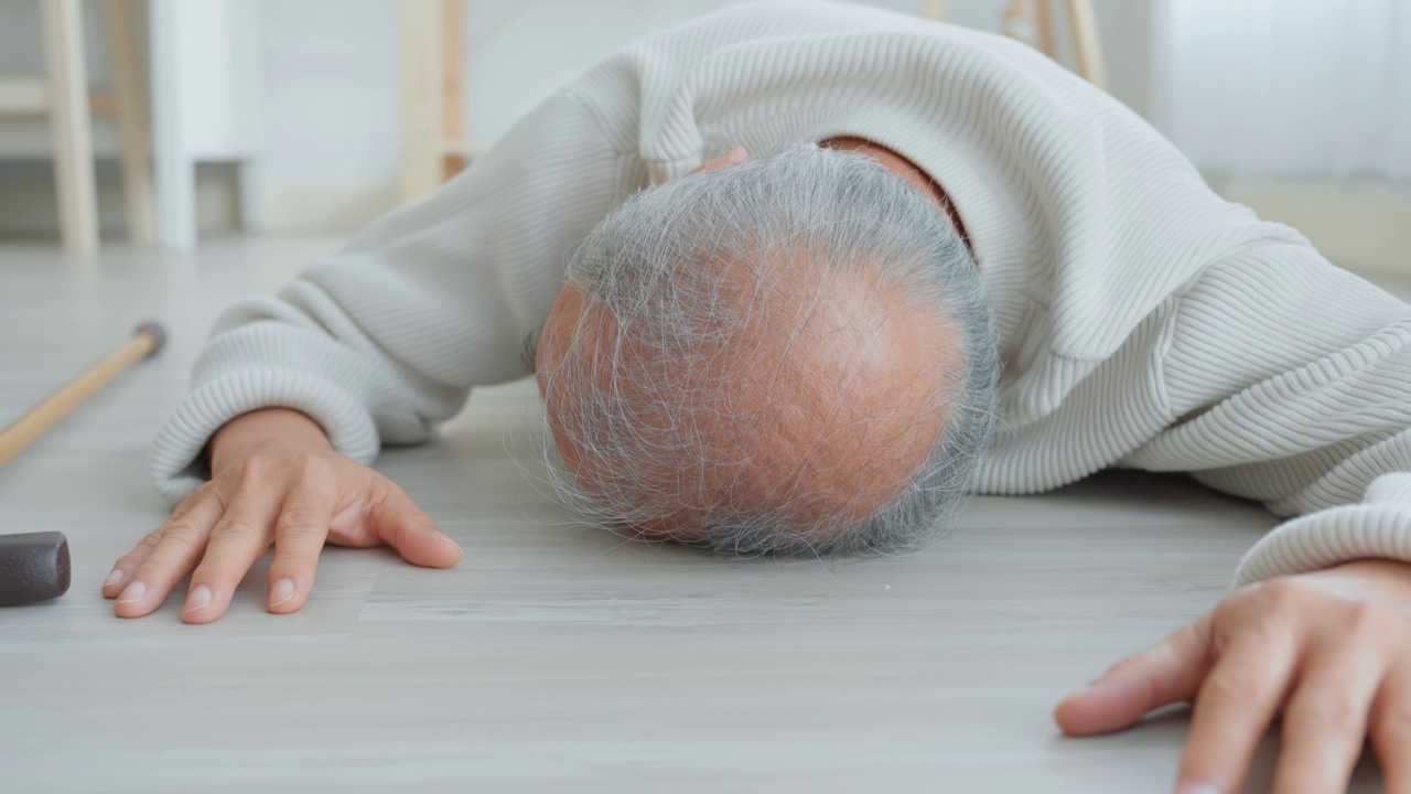 亚洲老年男性在家中与助行器行走时摔倒在地。老人年迈成熟的爷爷退休后在家里的客厅独自做物理治疗后发生了事故。视频下载