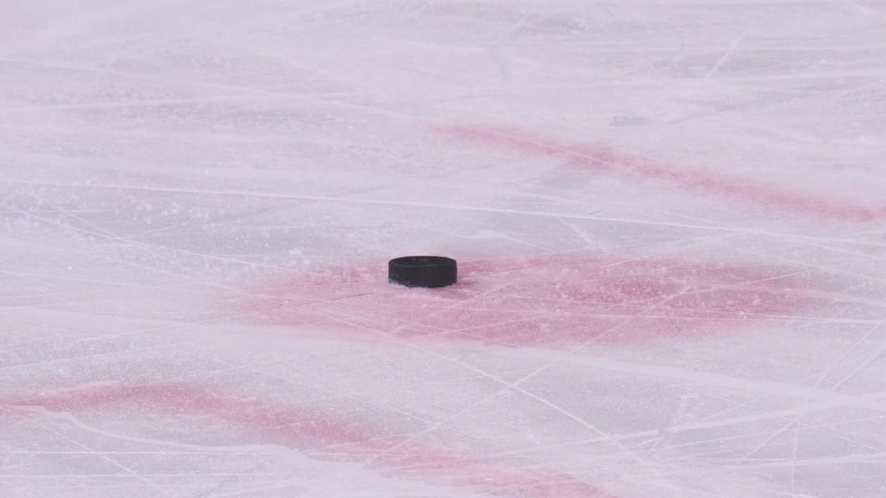在有划痕的冰场上的黑色冰球和滑冰曲棍球运动员视频素材