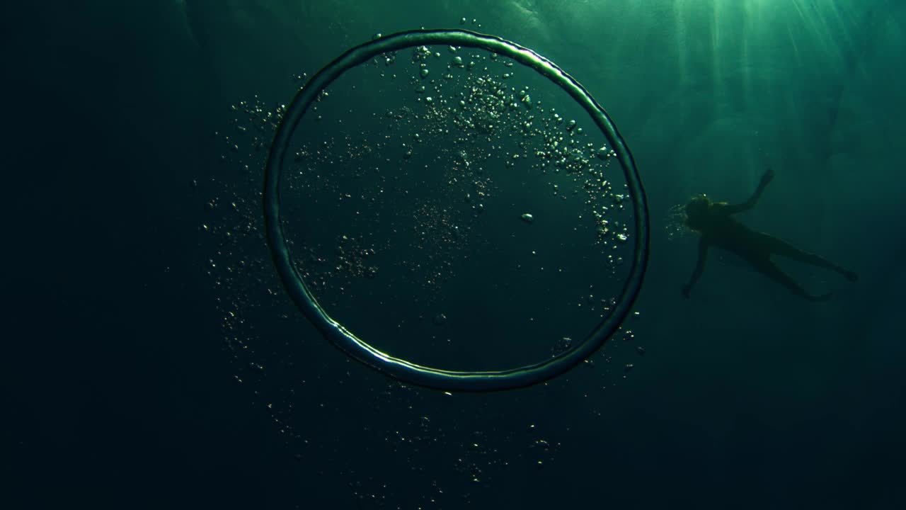 女人在海里游泳。底部视图的人浮潜在海面和泡沫环移动在深度视频下载