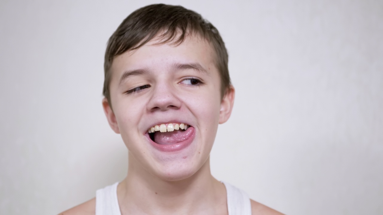 微笑的青少年与嘴手势，显示他的牙齿，舌头。近距离视频素材