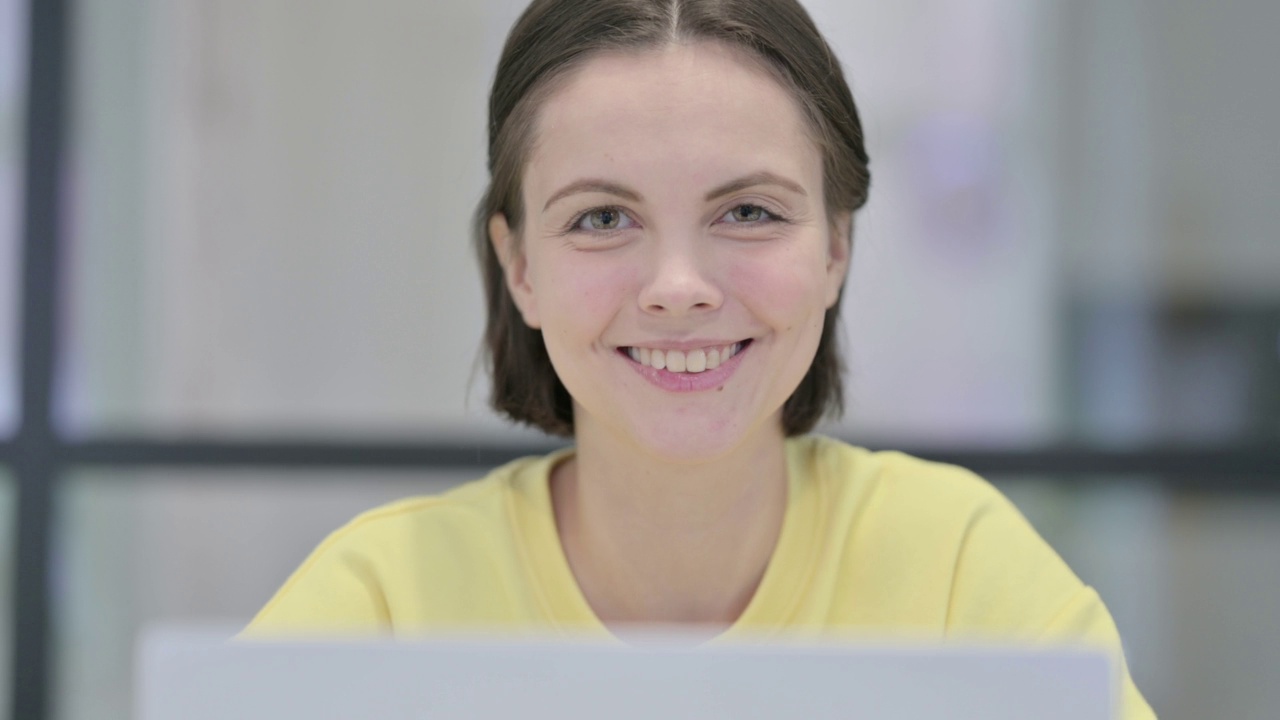 特写的女人与笔记本电脑在相机微笑视频素材