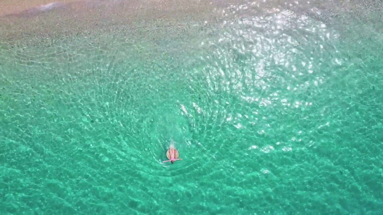 女子游泳和漂浮在海边的水与甜甜圈浮动鸟瞰图股票视频视频素材