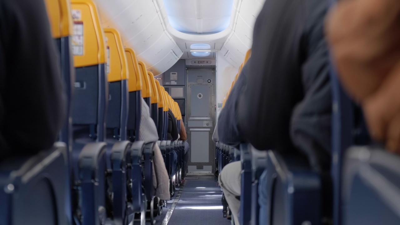 飞机过道，乘客在飞行过程中坐在自己的座位上。视频素材