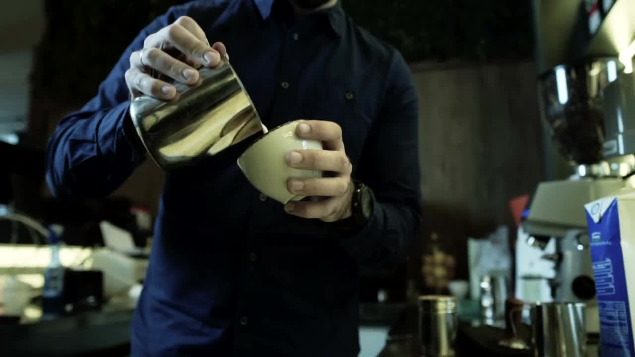 咖啡师在咖啡馆的热咖啡上制作拿铁艺术图片叶子和心。股票视频视频素材